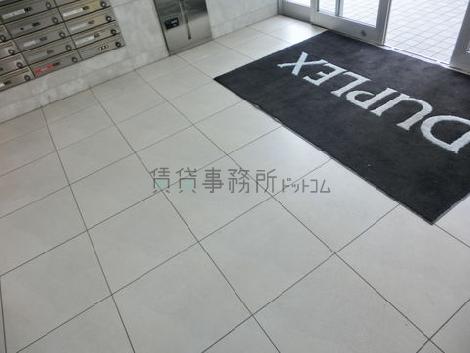 玄関の扉の下にビル名の入ったカーペットが敷かれています